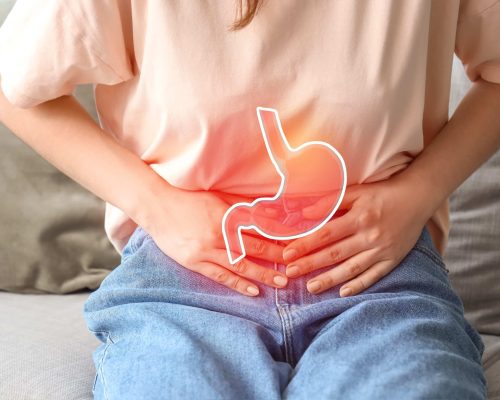 Junge Frau auf dem Sofa, die an Bauchschmerzen leidet