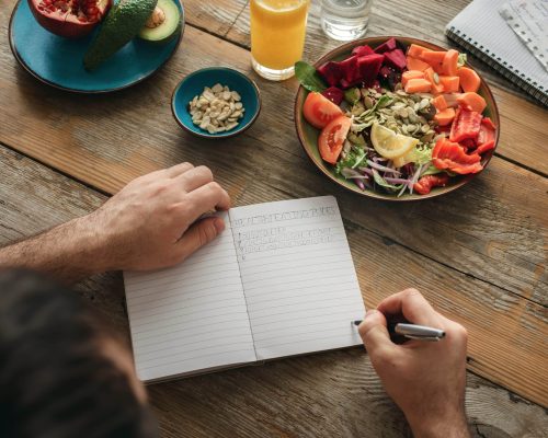 Ein Mann erstellt eine Liste mit gesunden Lebensmitteln. Aufklärung Ernährungsmythen, GASTEO Magazin